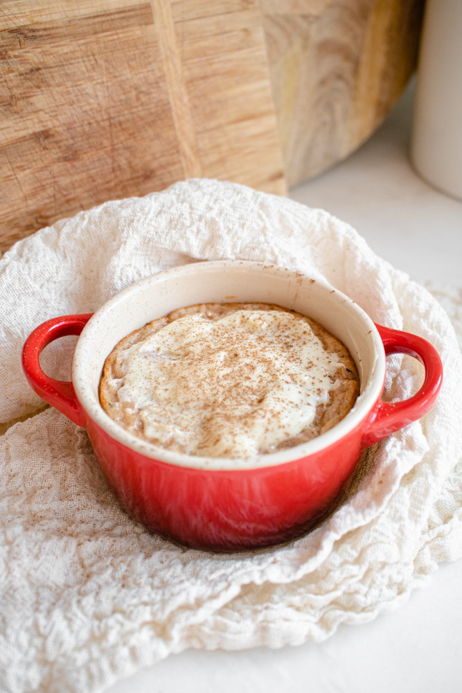 Baked oatmeal served in a ramekin with cream cheese frosting on top