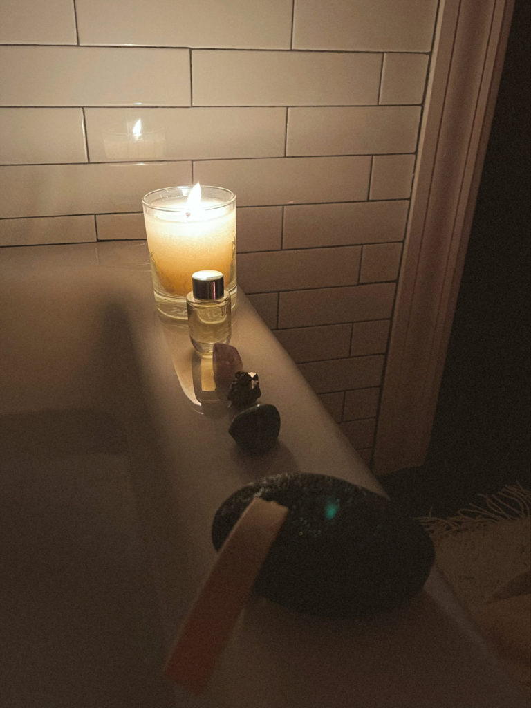 bathtub with lit candle and crystals